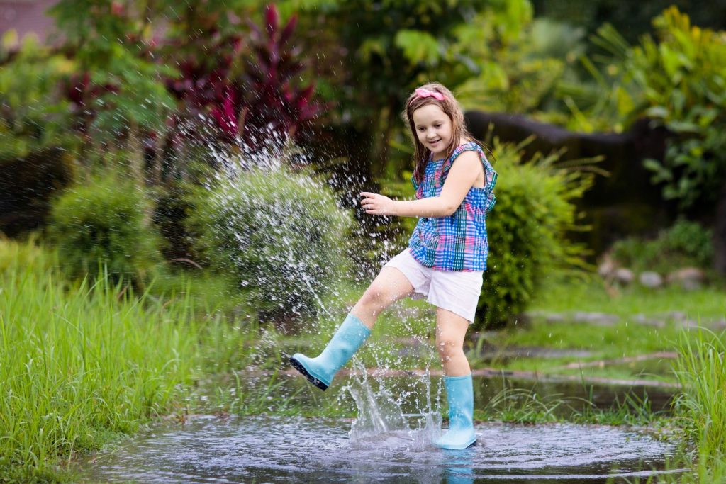Child dancing in the rain as outdoor summer activities for kids