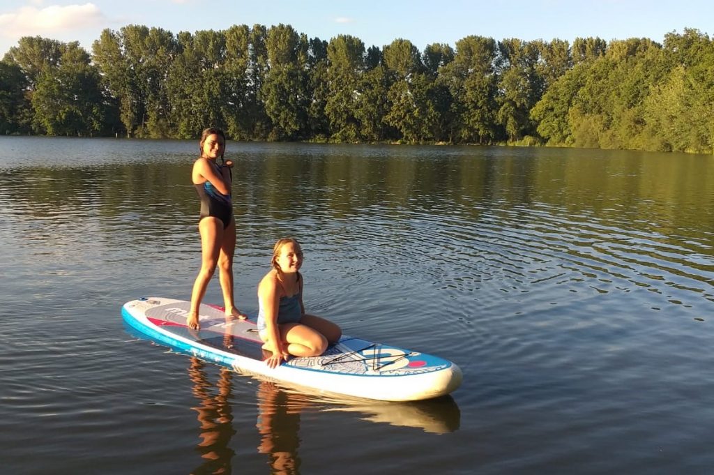 Two kids on a stand up paddling board